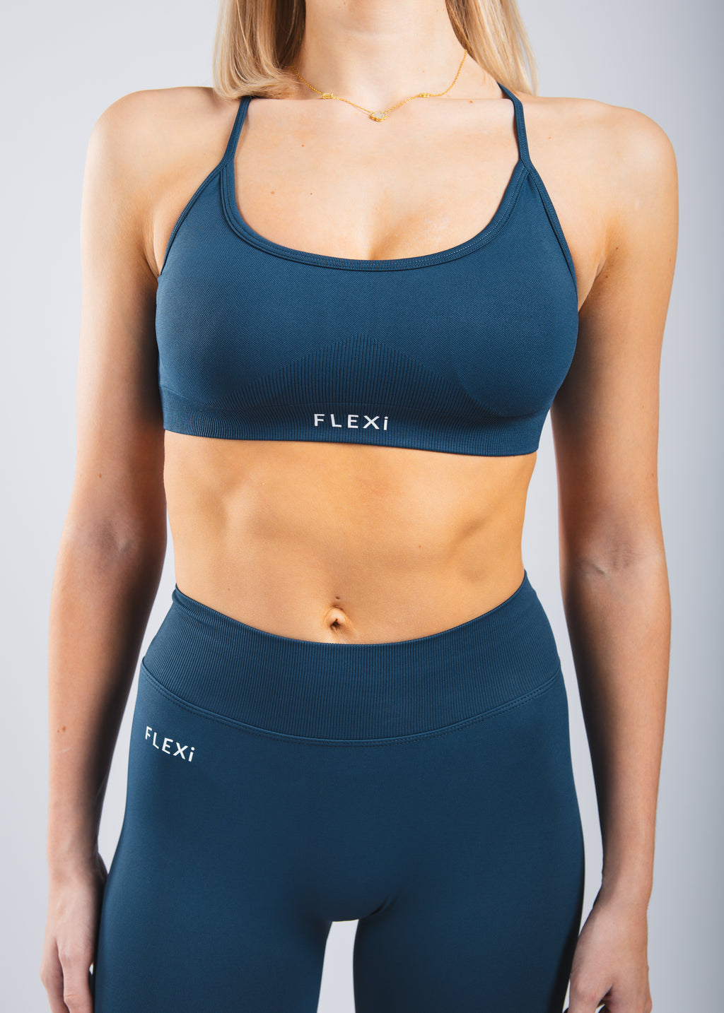 Person wearing a navy blue sports bra and leggings with 'FLEXI' branding on a gray background